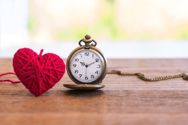 ketting antieke stijl zakhorloge met hart van breiende wol op een houten oppervlak