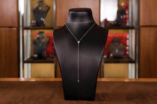 Ketting gemaakt van witgoud met diamanten op een standaard in mode-sieraden boetiek. Zwarte stand nek met luxe sieraden, vrouwen accessoires in etalage.