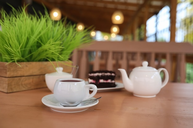 Photo kettle with a drink and dessert in street cafe. tea in the kettle cup on the table. breakfast with tea and cakes at the cafe.