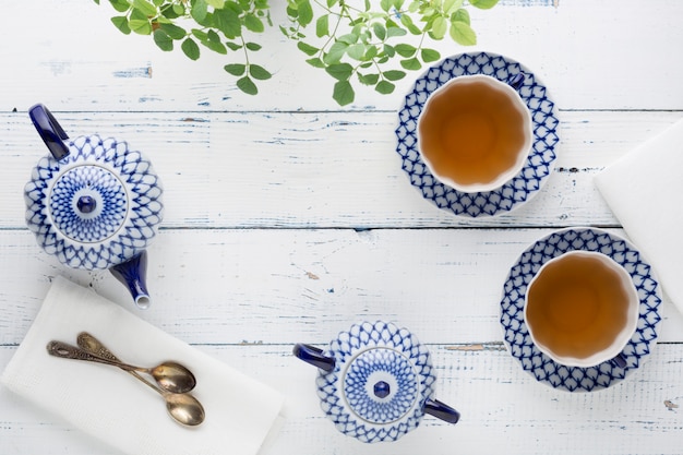 Foto bollitore con tè fresco e una tazza di ceramica sul tavolo. set da tè in ceramica con pittura artistica.