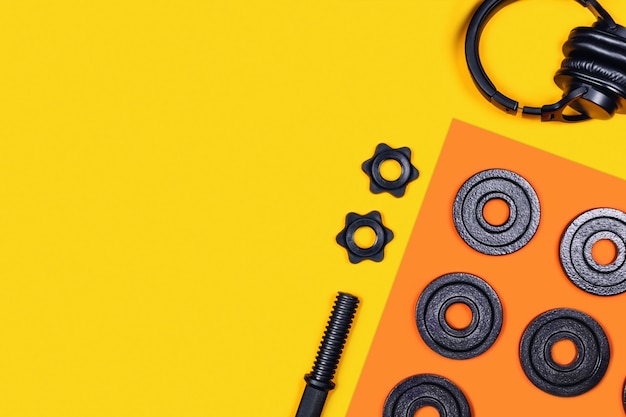 Photo kettlebell and headphones on color table.