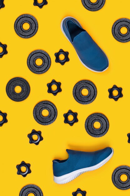 Kettlebells, dumbbells and sneakers on yellow background