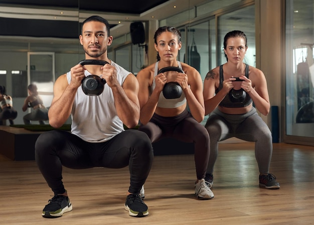 Kettlebells zijn een geweldige workout Volledig portret van drie jonge atleten die trainen met kettlebells in de sportschool