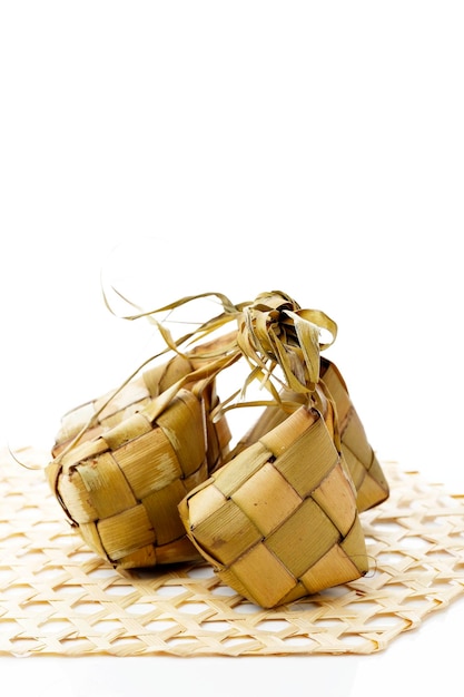 Кетупат или рисовые клецки специальное блюдо, подаваемое на ид мубарак ид аль фитр на белом фоне кетупат - это рисовая оболочка, сделанная из молодых кокосовых листьев