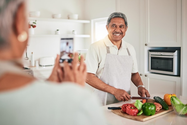 Keuken koken senior koppel en telefoon foto van oude man echtgenoot of voedingsdeskundige persoon met geheugenfoto Veganistische groenten of mensen die webvideo opnemen glimlach of lunch voedselingrediënten snijden