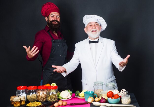 Keuken strijd. Twee bebaarde professionele koks in uniform. Kooktijd.