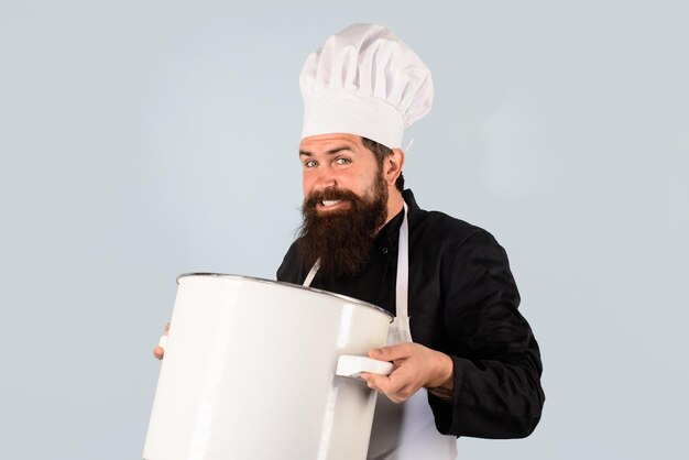 Keukengerei knappe mannelijke chef-kok met pan chef-kok man in hoed houdt pan man in chef-kok uniform met