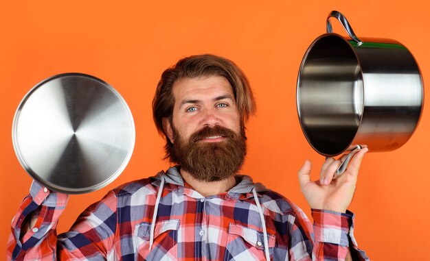 Keukengerei. Kookgerei. Man met steelpan. Gelukkig chef-kok met kookpot. Keuken reclame.