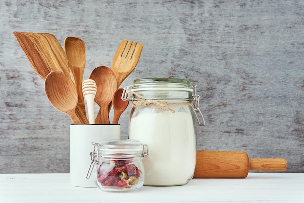 Keukengerei met houten bestek en deegrol op een witte tafel