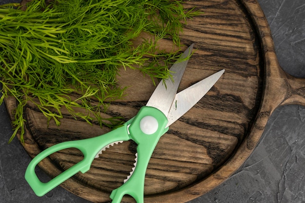 Foto keukenschaar die dille snijdt in de keuken op een snijplank