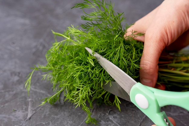 Keukenschaar die dille snijdt in de keuken op een snijplank