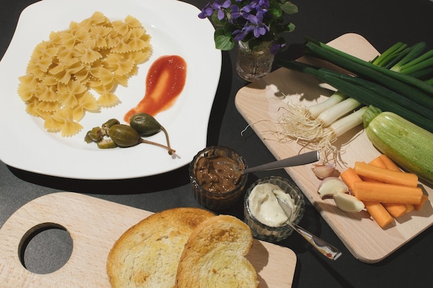 Keukentafel met platen, houten planken, groenten, brood, pasta, boog en viooltjes.