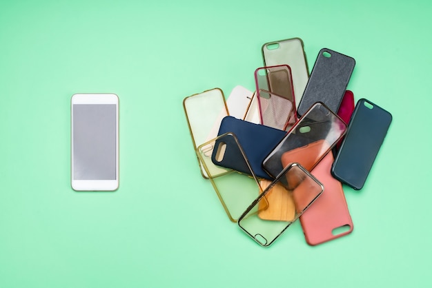 Keuze uit veelkleurige plastic achtercovers voor mobiele telefoons op groene achtergrond met een smartphone aan de zijkant