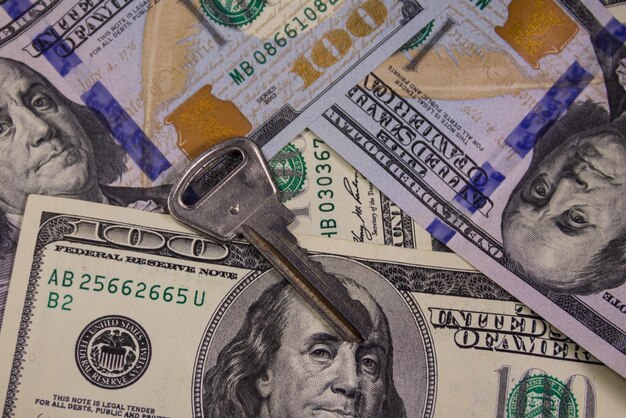 Key on the background of the American one hundred dollar bills. Concept of buying or renting home