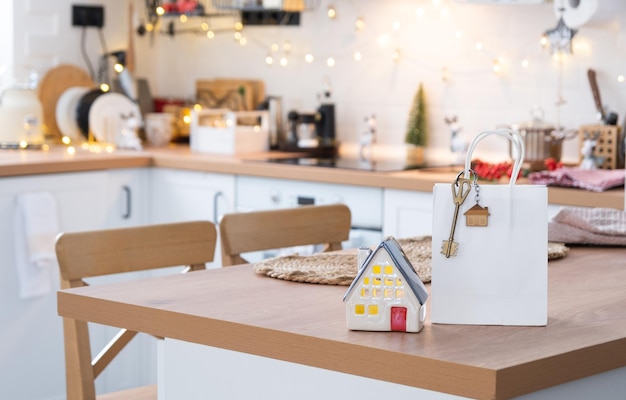 Key to the house on cozy home with Christmas decor and packages on table of festive kitchen Gift for New Year Building design project moving to new house mortgage rent and purchase real estate