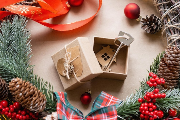 Key to house with keychain on cozy home in gift box with\
christmas decor packaging pack present for new year christmas\
building project moving to new house mortgage rent purchase real\
estate