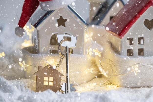 크리스마스 장식이 있는 아늑한 집에 열쇠고리가 있는 집의 열쇠 새해 선물 크리스마스 빌딩 디자인 프로젝트 이사 새 집 모기지 임대료 및 부동산 구입