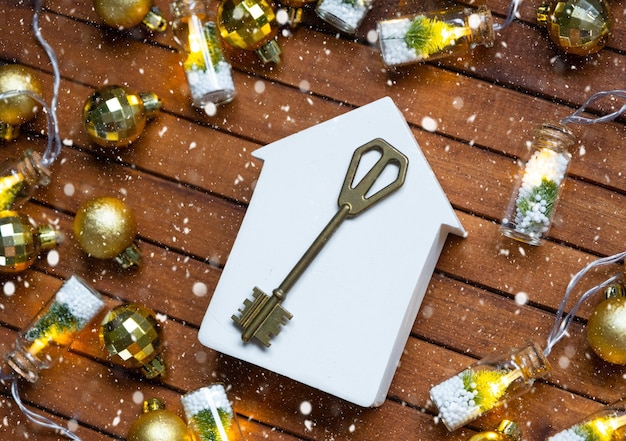 Key to house with a keychain tiny home on wooden background with Christmas decor layout