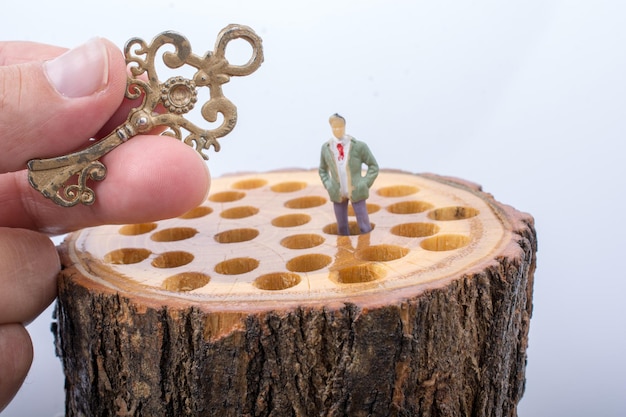 Key and little man figurine places on wooden log