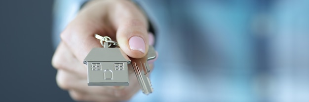 Key with house keychain is pulled forward getting loan for housing construction concept
