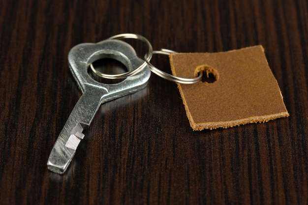 Key with leather trinket on wooden background