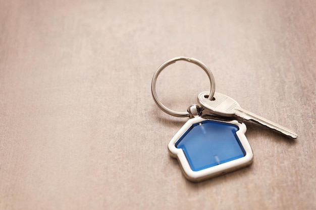 Key with trinket in shape of house on wooden table