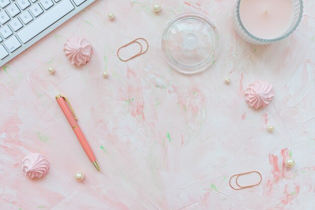 Keyboard, clip, candle and pen on pink desk