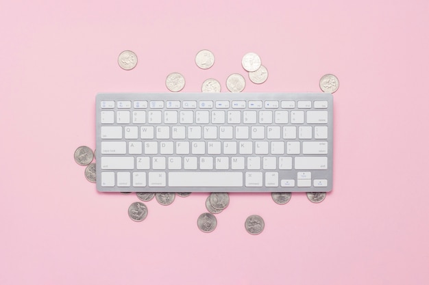 Keyboard and coins on a pink background. Dollar sign The concept of income on the Internet, remote work. Flat lay, top view.