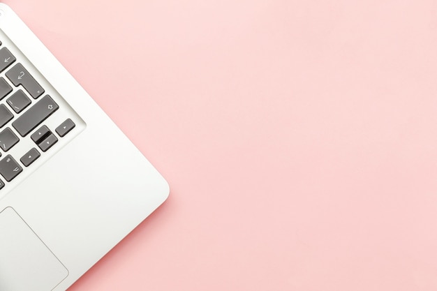 Photo keyboard laptop computer isolated on pink pastel desk background. modern information technology and sofware advances. freelance home office programmer or designer workspace concept