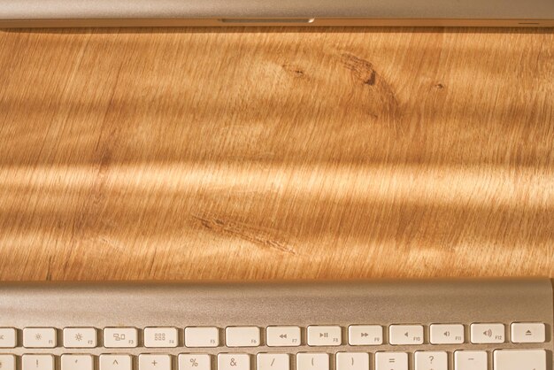 Keyboard and laptop detail on a wooden table. Communication banner.