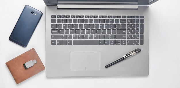 Клавиатура ноутбук, смартфон, кошелек, ручка, флэш-накопитель usb на белом фоне. концепция фриланса. вид сверху.