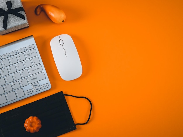 オレンジ色の背景にキーボード マウス黒医療マスク ギフト ボックスとカボチャ