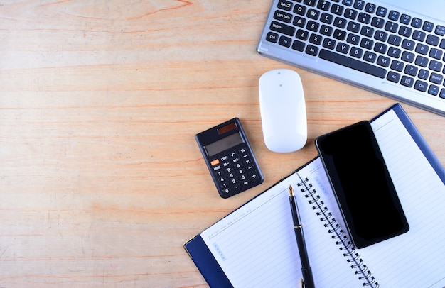 Keyboard and mouse, fountain pen, notebook, calculator and smartphone on a table