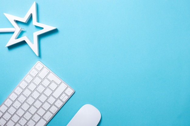 Keyboard, mouse and star on blue background flat lay