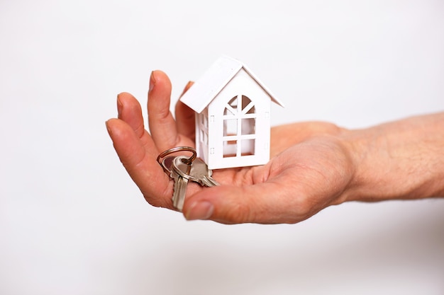 Keychain with house keys on a man's hand on a white background. Real estate agent, new home sale, mortgage, moving, banking, repair and construction