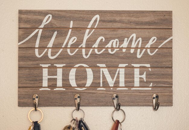 Photo keys hanging on wooden and metal key hook with welcome home message