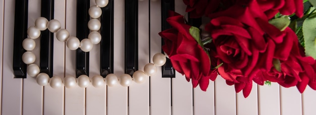 Keys of a piano with pearl necklace and bouquet of roses