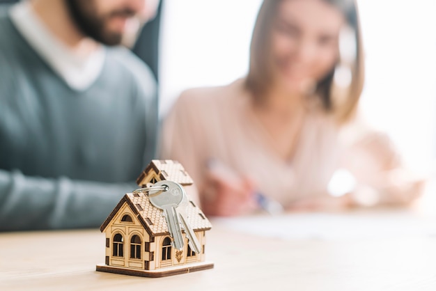 Photo keys and small house near blurred couple