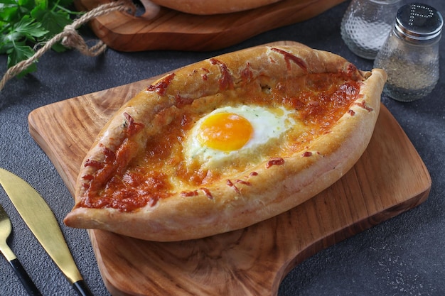 Khachapuri in Adjarian Open pie with suluguni cheese and egg yolk in the form of a boat on a wooden board Traditional Georgian cuisine