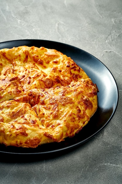 Khachapuri with salty melted cheese in a plate Concrete background