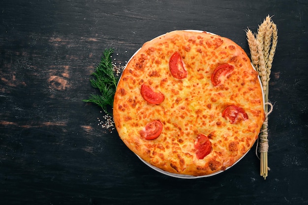 Khachapuri with tomatoes and cheese Georgian cuisine On the old wooden background Free space for text Top view