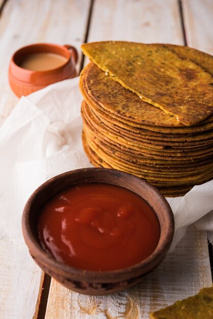KhakhraまたはKhakraは薄いクラッカーで、人気のあるジャイナ教、グジャラート語、ラジャスタン語の朝食用食品です。ホットティーとトマトケチャップを添えて。カラフルまたは木製の背景の上