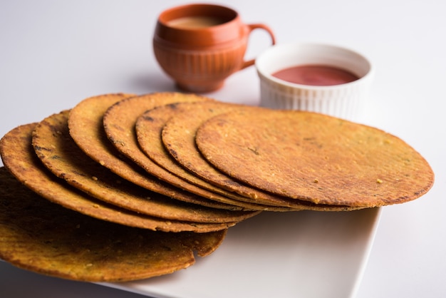 Khakhra or Khakra is a thin cracker is a popular Jain, Gujarati and Rajasthani  breakfast food. Served with Hot Tea and Tomato Ketchup. Over colourful or wooden background