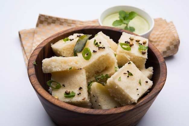 ご飯またはウラドダルでできたカマンホワイトドクラは、インドのグジャラート州で人気の朝食またはスナックのレシピで、グリーンチャツネとホットティーを添えています。セレクティブフォーカス
