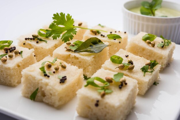 Khaman white Dhokla made up of rice or urad dal is a popular breakfast or Snacks recipe from Gujarat, India, served with Green chutney and hot tea. Selective focus