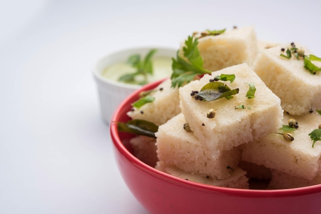 Khaman white Dhokla made up of rice or urad dal is a popular breakfast or Snacks recipe from Gujarat, India, served with Green chutney and hot tea. Selective focus