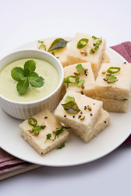 Khaman witte Dhokla bestaande uit rijst of urad dal is een populair ontbijt- of snackrecept uit Gujarat, India, geserveerd met groene chutney en hete thee. Selectieve focus