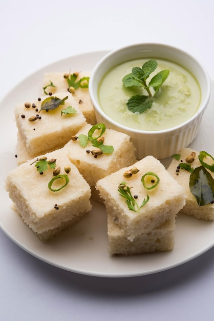 Khaman witte Dhokla bestaande uit rijst of urad dal is een populair ontbijt- of snackrecept uit Gujarat, India, geserveerd met groene chutney en hete thee. Selectieve focus