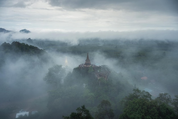 Khao Na Nai Luang Dharma Park、タイ、スラートターニーの朝の霧の丘にある古代の塔