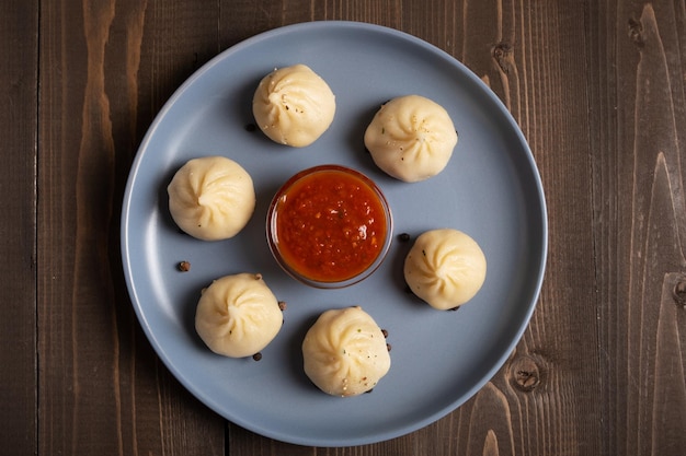 Khinkali on a blue plate with spicy tomato sauce Dish of Georgian cuisine